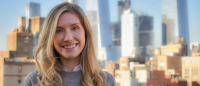 Person smiling in front of skyline.